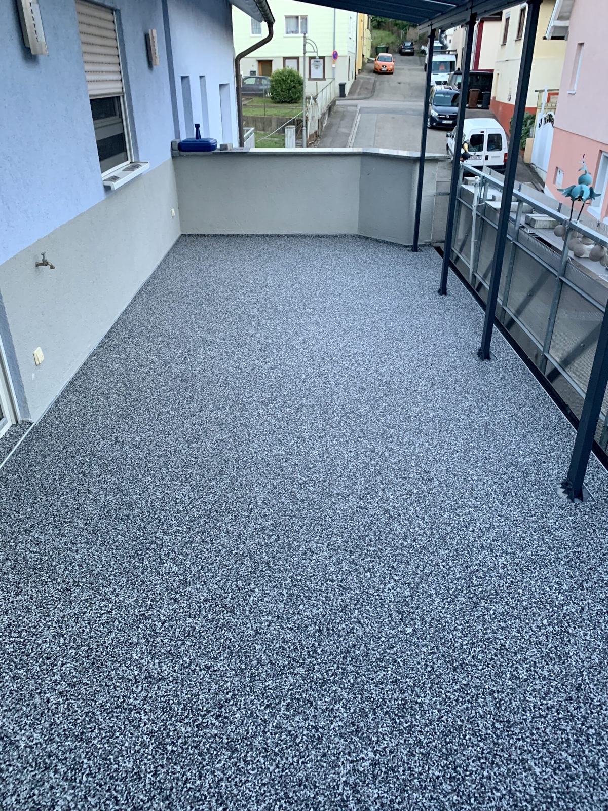 Balkon mit grauem Steinteppich und Blick auf den Ort