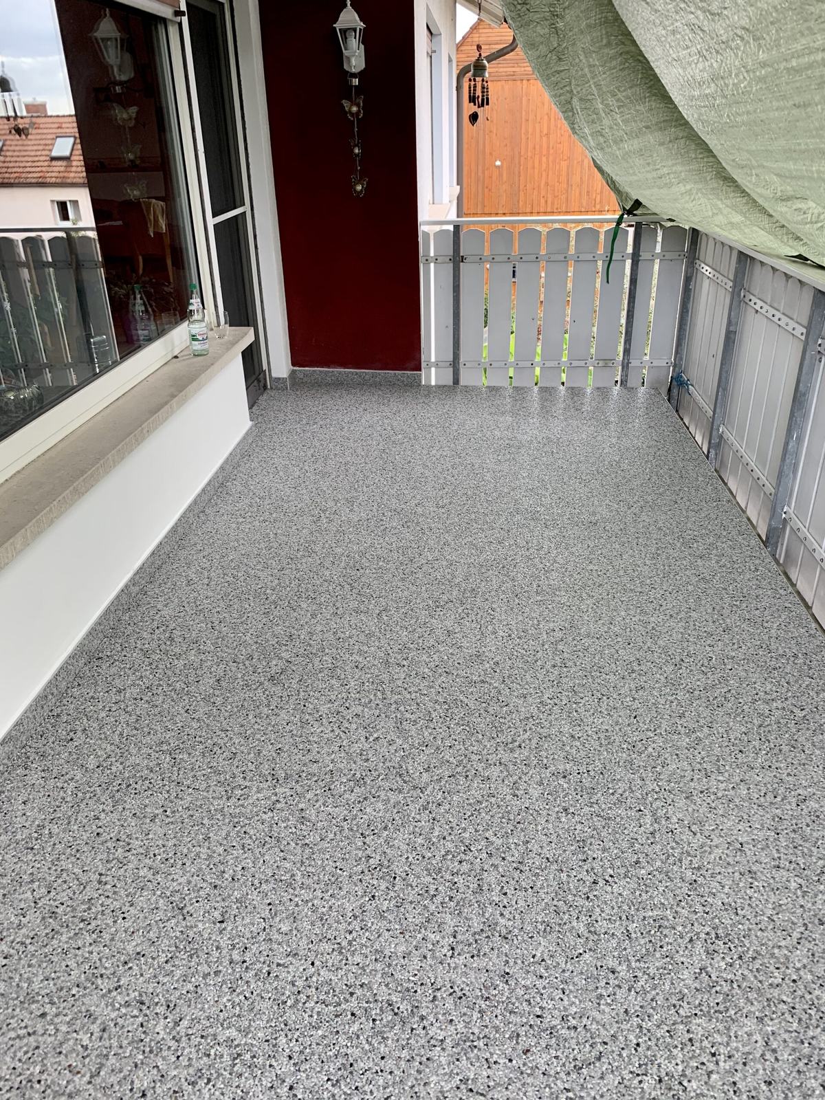 Balkon mit hellgrauem Steinteppich und Geländer