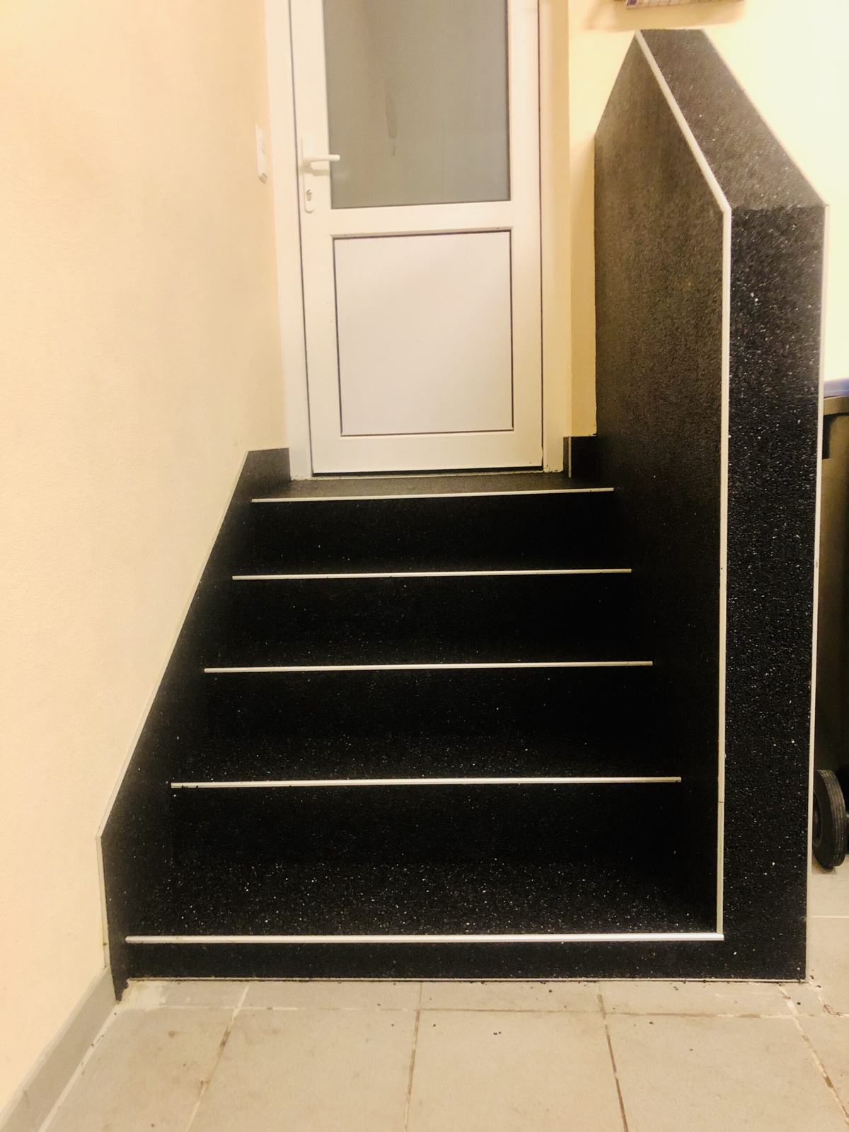 Hauseingang mit schwarzem Steinteppich und heller Trittkante