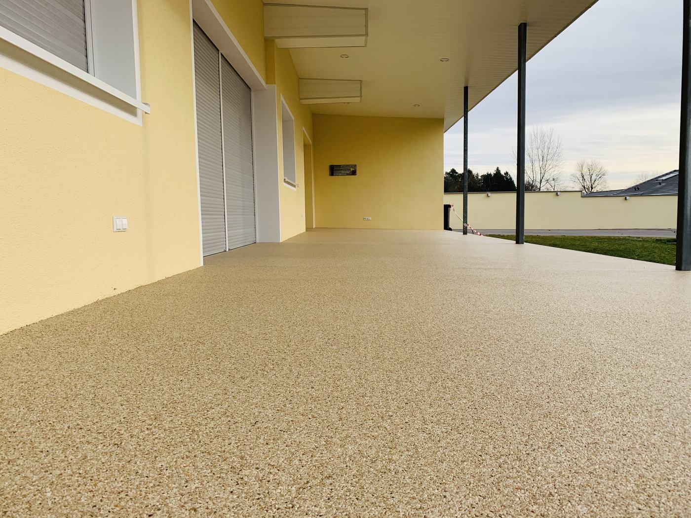 Lange Loggia mit sandfarbenem, fugenlosem Steinteppich