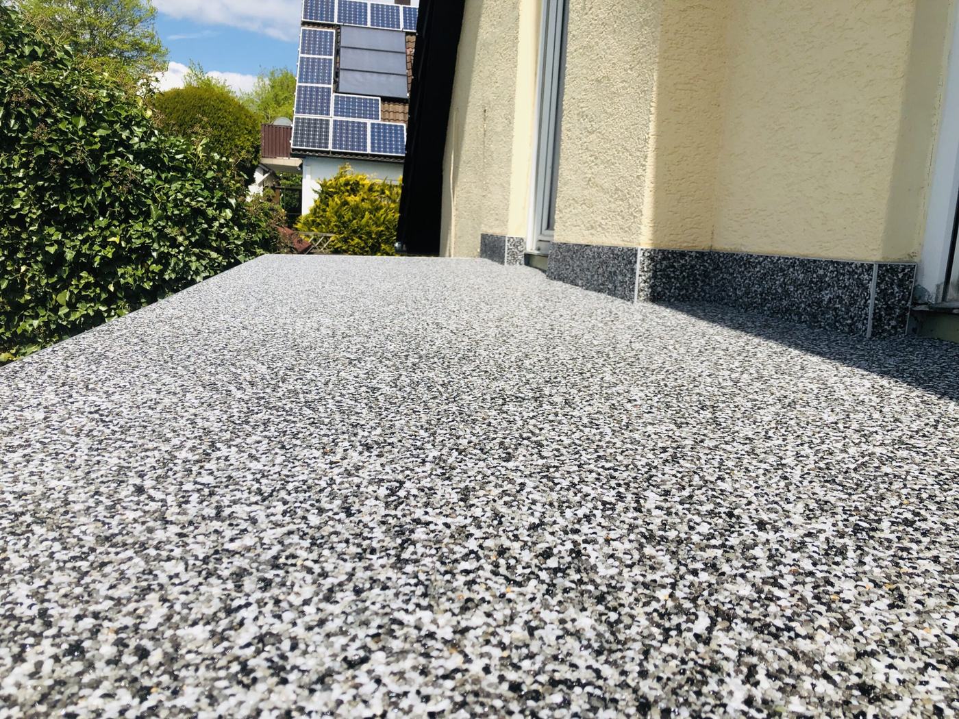 Terrasse mit hellem Steinteppich vor einer Hauswand