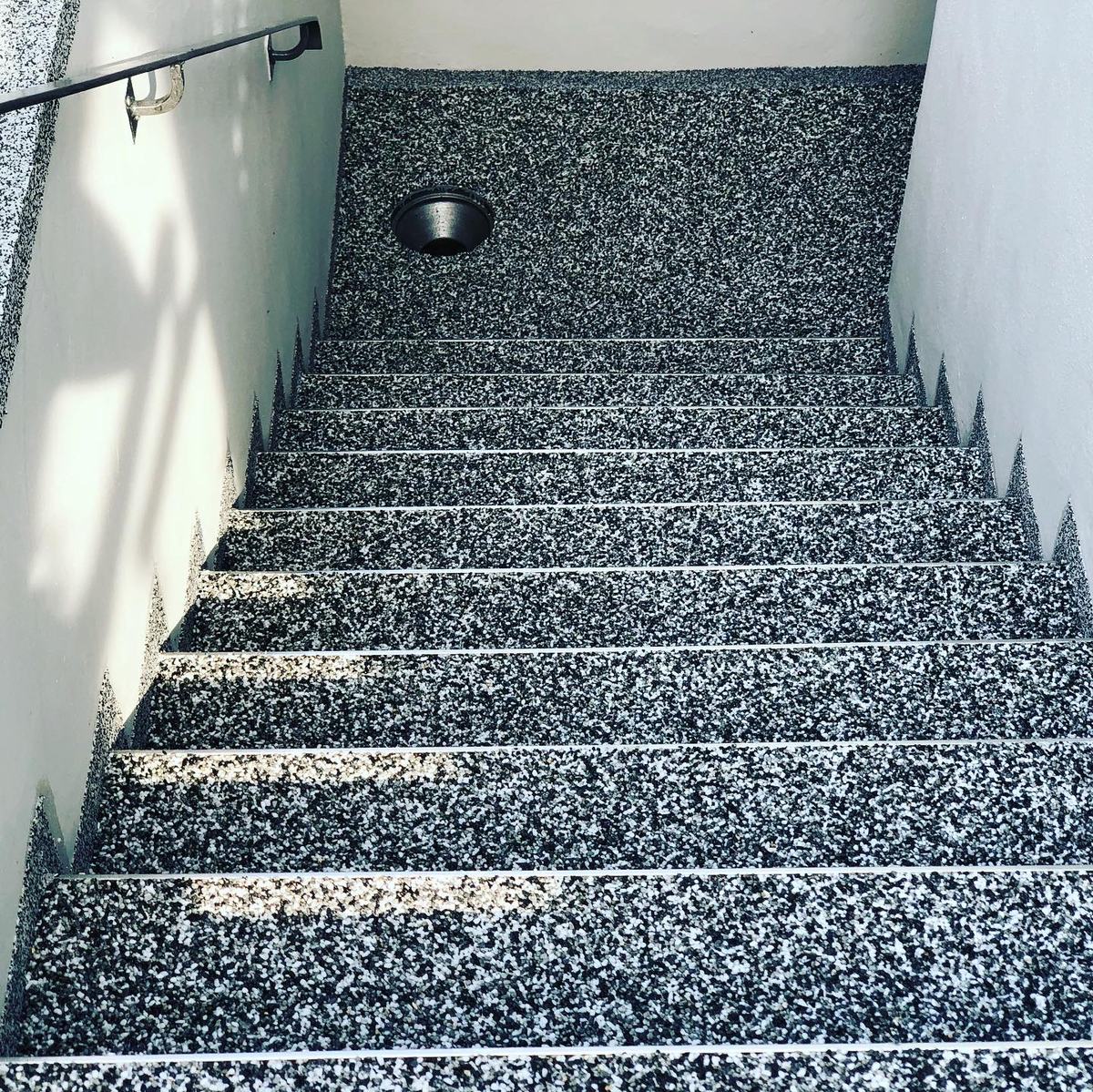 Treppenabgang mit grauem Steinteppich und Ablauf